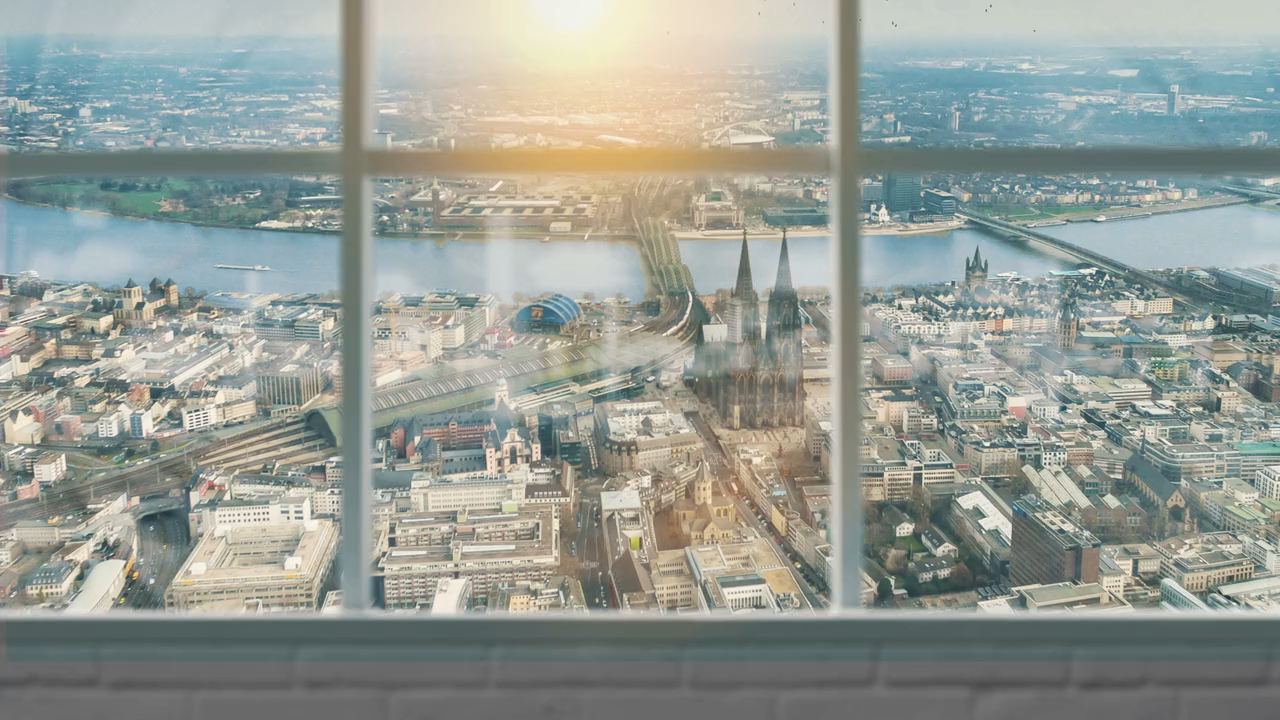 Blick aus einem Sprossenfenster über Köln: der Dom, die Hohenzollernbrücke und der Rhein im Gegenlicht