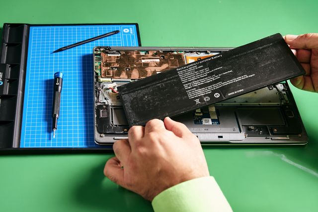 Geöffnetes Notebook auf der Werkbank in Bensberg, der Akku wird ausgebaut